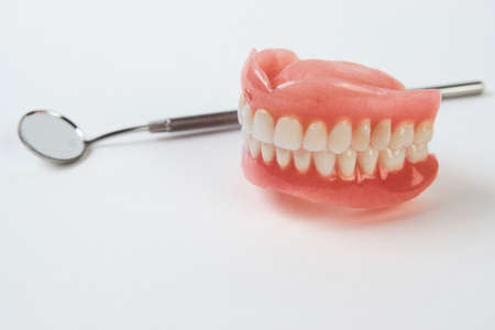 Artificial teeth on a white background with copy space. Dentist appointment, dentistry instruments...