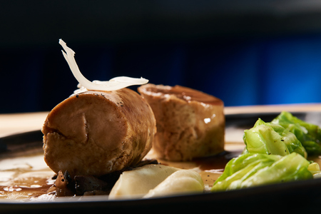 Baked chicken sausage meat with baked green cabbage. Goose breast galantine, mushroom fricassee, young cabbage and sauce.の写真素材