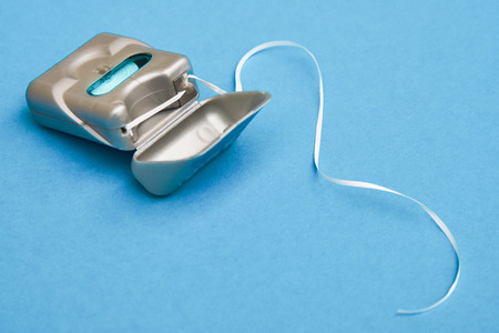 Dental floss on a blue background with copy space. Daily oral hygiene for healthy teeth. Tooth cleaning equipment for mouth close-upの写真素材