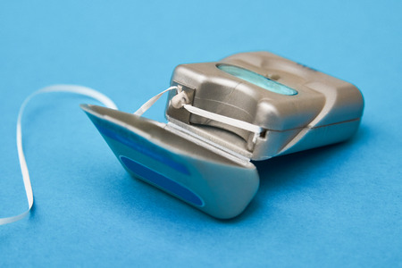 Dental floss on a blue background with copy space. Daily oral hygiene for healthy teeth. Tooth cleaning equipment for mouth close-upの写真素材