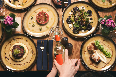 Friends Company gathering for Christmas or New Year party dinner at festive table. Flat-lay of human hands eating meals and celebrating holiday, top view. People eat healthy food and drink alcoholの写真素材