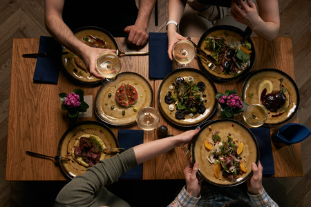 Top view of friends having lunch. Enjoying dinner with friends. Group of people having dinner together while sitting at the rustic wooden table.の写真素材