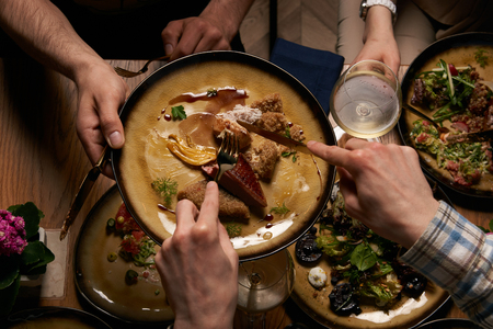 Friends having dinner. Top view of people having dinner together while sitting at wooden tableの写真素材
