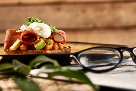 Classic English breakfast toast bread with poached egg, bacon, beans, truffle oil, avocado and pickled onions, close-up Healthy vitamin food and spring diet conceptの写真素材