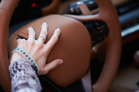 Woman driving yellow sports car with hand hold steering wheel. Close-up of female hands holds steering wheel of super car, outdoorsの写真素材