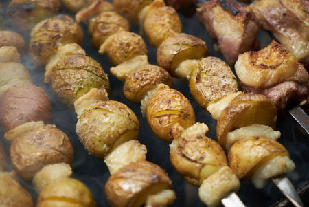 Grilled shish kebab with vegetables. BBQ grill with lamb meat and potatoes. Preparation of shish kebab on skewers, close-up.の写真素材
