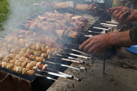 Preparation of shish kebab on skewers, close-up. Grilled shish kebab with vegetables. BBQ grill with lamb meat and potatoesの写真素材