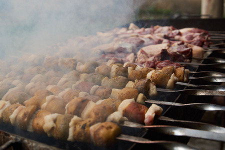 Preparation of shish kebab on skewers, close-up. Grilled shish kebab with vegetables. BBQ grill with lamb meat and potatoesの写真素材