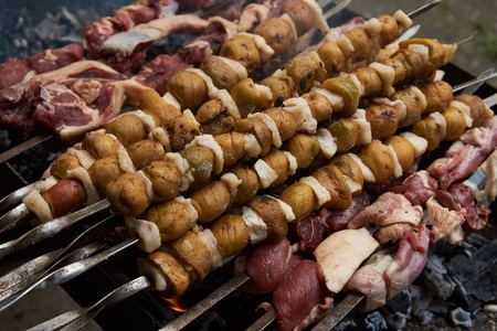 Preparation of shish kebab on skewers, close-up. Grilled shish kebab with vegetables. BBQ grill with...