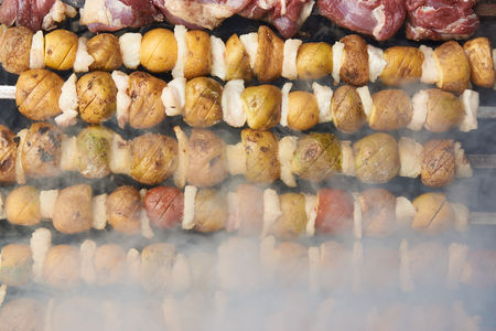 Preparation of shish kebab on skewers, close-up. Grilled shish kebab with vegetables. BBQ grill with lamb meat and potatoesの写真素材