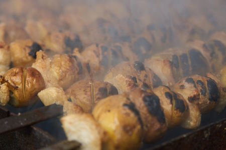 Preparation of shish kebab on skewers, close-up. Grilled shish kebab with vegetables. BBQ grill with...