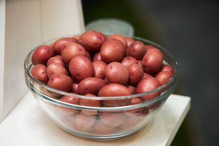 Red potatoes in a glass bowl on kitchen shelf, close-up. Fresh potato foodの写真素材