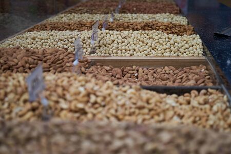 Variety of nuts on market counter, close-up. Mix of fresh nuts with price tag, selective focusの写真素材