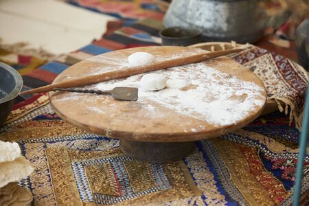 Traditional turkish cuisine pita bread preparing. Dough on a round wooden board with flour dough and rolling pinの写真素材