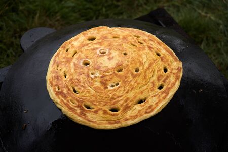 Pita bread baking on a saj or tava on fire, close-up. Traditional arabic pita bread cooking on fire. Preparing or making borekの写真素材