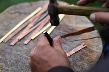Handmade work with metal engraving. Craftsman working outdoors, close-up.