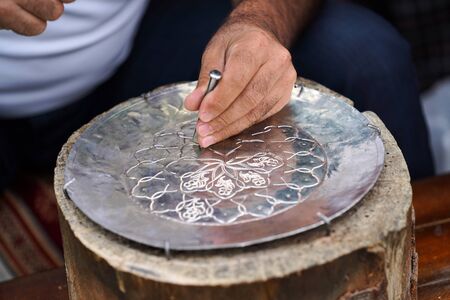 Handmade work with metal engraving. Craftsman working outdoors, close-up.
