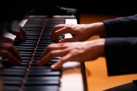 Closeup man's hand playing piano. Music performer's hand playing the grand piano keyboard