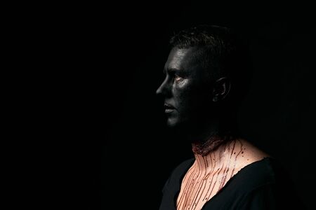 Halloween makeup portrait of a young man with black face and slit throat