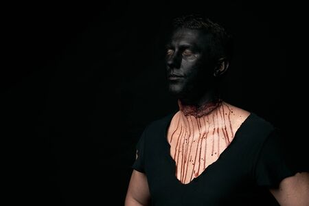 Halloween makeup portrait of a young man with black face and slit throat