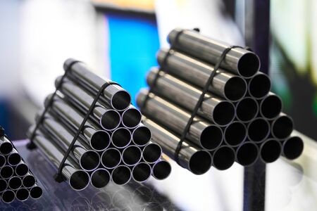Steel pipes against industrial blurred background. Stack of Aluminum pipes, close-up. Manufacturing...
