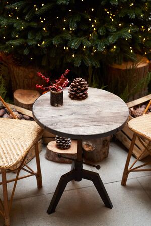 Christmas tree with festive table with mandarins, oranges and pine tree cone. Citrus fruits oranges and tangerine on wooden table, close-up. Xmas party or New Year tableの写真素材