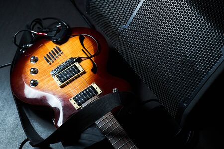 Yellow electric guitar and black amplifier on a dark background. Indoor concert stage with guitar...