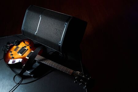 Yellow electric guitar and black amplifier on a dark background. Indoor concert stage with guitar...