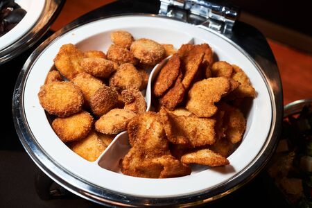 Crispy chicken nuggets tray, close-up. Table in a restaurant with food snacks at an event, indoorsの写真素材