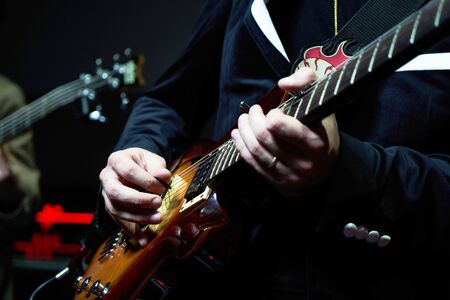 Guitarist hands plays guitar solo, close-up. Guitarist with electric guitar on stage. A singer man...