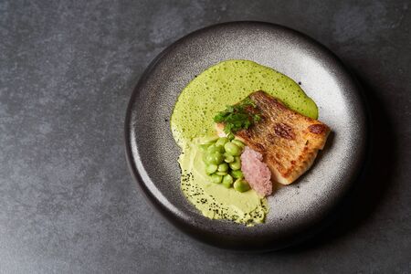 Pike perch fillet with green bean edamame puree and sauce, close-up, top viewの写真素材