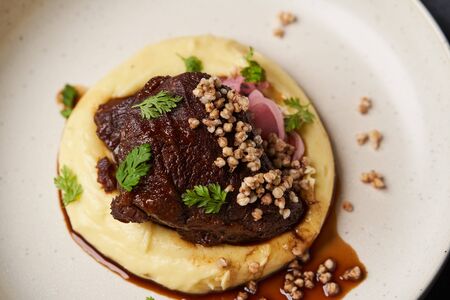 Stewed veal cheeks with mashed potatoes on a white plate, close-up. Luxury restaurant dish Stewed veal cheeksの写真素材