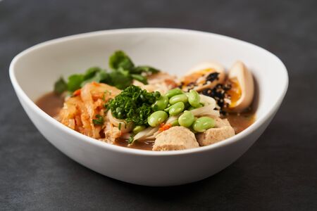 Asian noodles soup, ramen with chicken, tofu, vegetables and egg, close-up. Ramen noodle soup with...