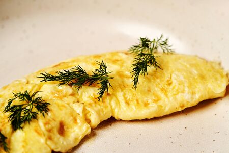 Traditional breakfast omelette with bacon, tomatoes, mushrooms, onion and cheese on a white plate on dark background with copy space, close-up. Egg omelette with parsley dill herbs.の写真素材
