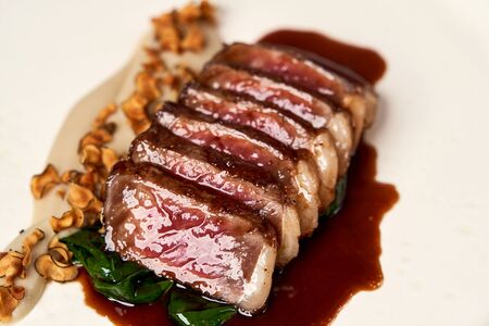 Sliced lamb meat and mashed potatoes on a white plate on gray table background with copy space....