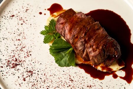 Filet mignon with mashed potatoes and pomegranate sauce. Filet mignon Steak with red wine sauce on white plate on gray background with copy space, close-upの写真素材