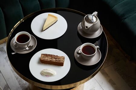 Afternoon tea with cake on restaurant table, close-up. Traditional tea ceremony. Sweets dessert cookies cake and teapot with cupsの写真素材