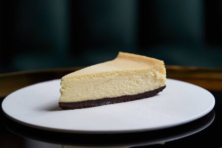 Cup of tea and slice of cheesecake on white plate on table, close-up.の写真素材