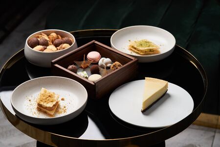 Coffee dessert on restaurant table. Sweet cookie snack, cake slices and chocolate candy on table, close-up. Coffee break timeの写真素材