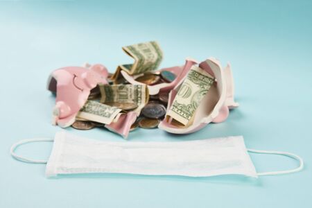 Medical mask and broken piggy bank with coins money on blueの写真素材