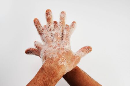 Man washing dirty hands with soap, close-up. Soapy male hands isolated on white background with copy space.  Hand washing medical procedure step. Personal hygieneの写真素材