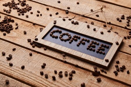 Coffee shop chalkboard frame. Blackboard with COFFEE text by coffee beans on wooden wall background. Hanging door sign boardの写真素材