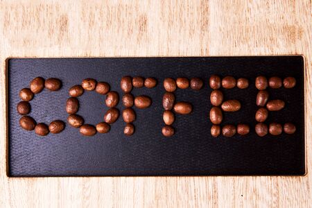 Coffee inscription with coffee beans on wooden board.の写真素材