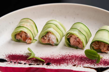 Sushi rolls with cucumber and treat fish. Cucumber rolls with salmon and beet on a white plate. Luxury restaurant seafood menuの写真素材