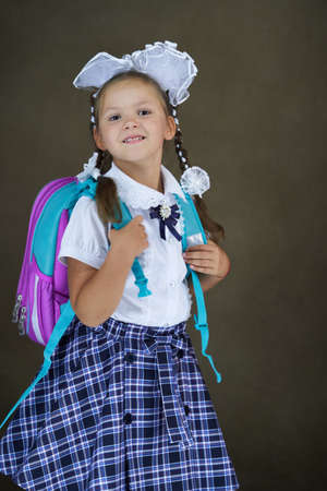 Student girl with school backpack. 6 years old girl with schoolbag on dark background, close-up. Back to school conceptの写真素材