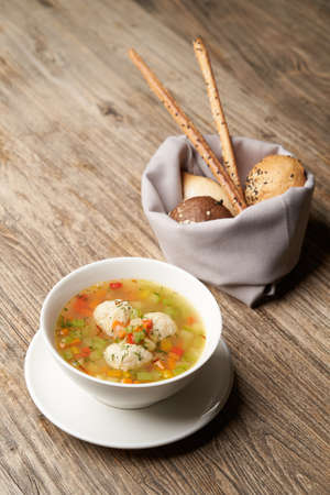 Soup with chicken meatballs and vegetables. White plate with Traditional Jewish passover dish matzo ball soupの写真素材