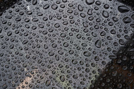Rain drops on glass background. Raindrops on glass with reflection, close-up. Water drops background. Autumn season weather.の写真素材