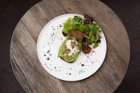 Toast Avocado with Poached Egg. Healthy Breakfast with toasted bread with avocado and poached egg on white plate. Luxury restaurant foodの写真素材