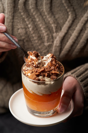 Woman eating Persimmon pudding. Woman having breakfast with Persimmon smoothie with yoghurt cream and chocolateの写真素材
