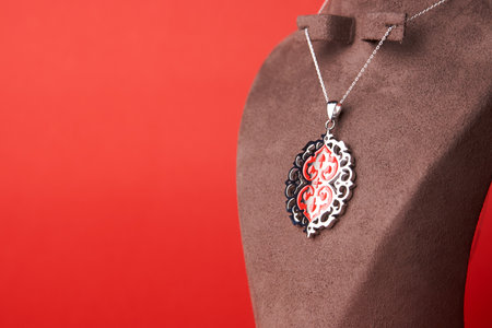 Silver necklace on red background. Platinum chain with silver pendant. Luxury female jewelryの写真素材